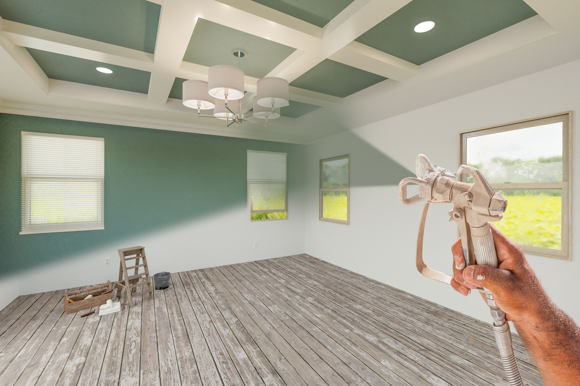Professional Spray Painter Holding Spray Gun Spraying Renovated Room Over Unfinished Room.
