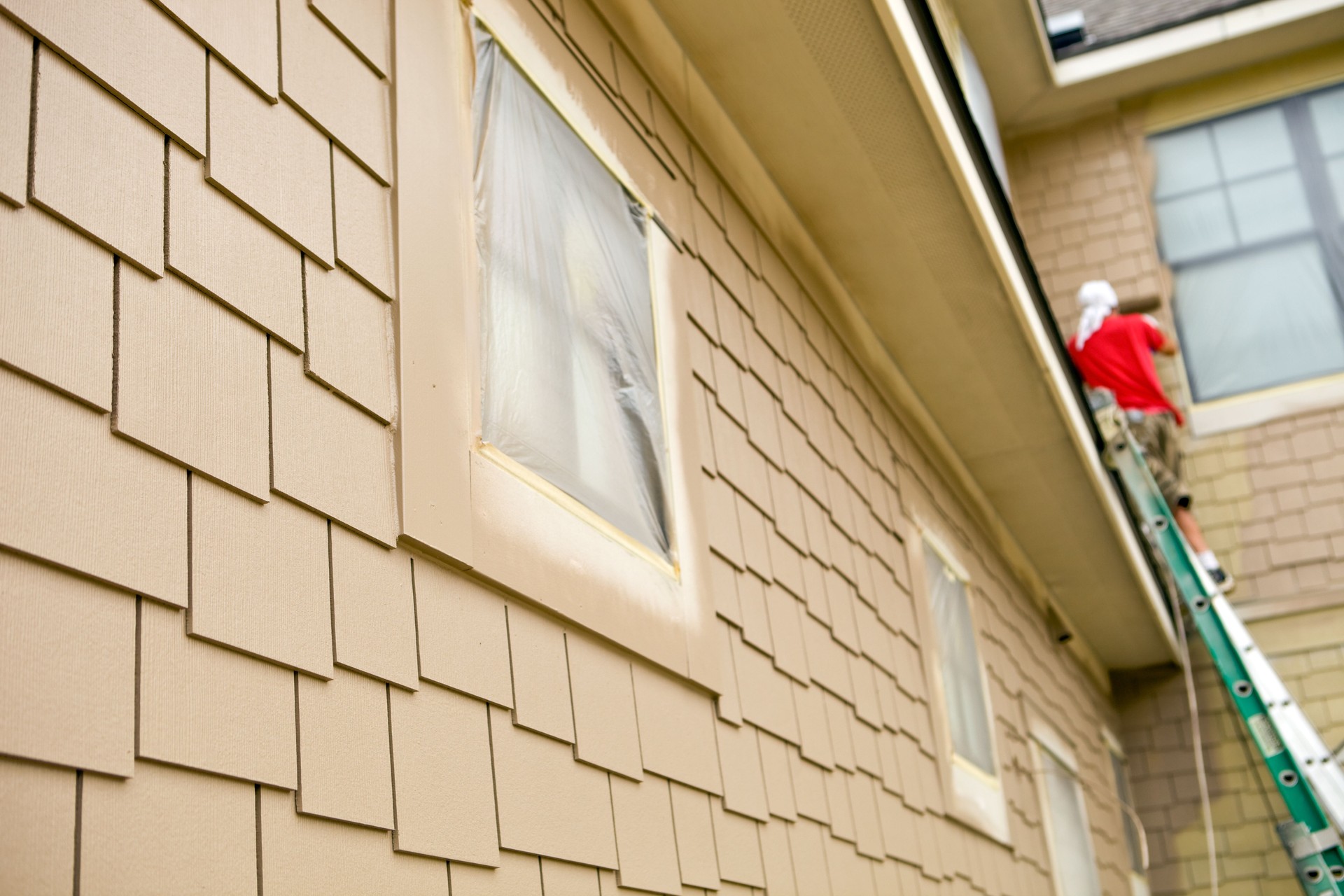 House Painter Rolling Paint on a New Home’s Siding